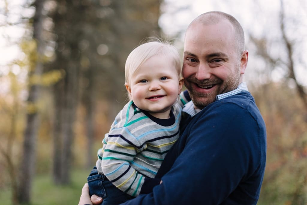 dad cuddling toddler smiling at session