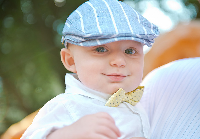 young wedding guest in newsboy cap and bowtie