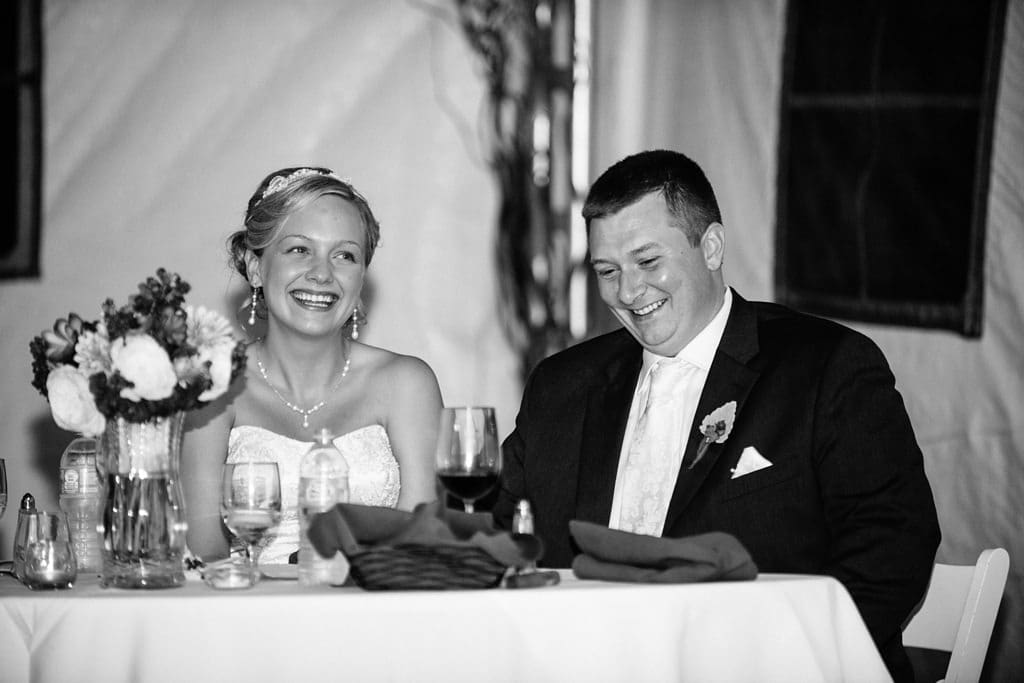 bride and groom listen to speeches at reception
