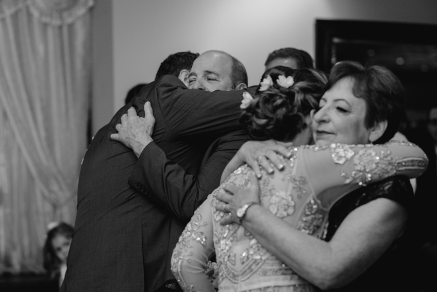 bride and groom hugging parents at wedding