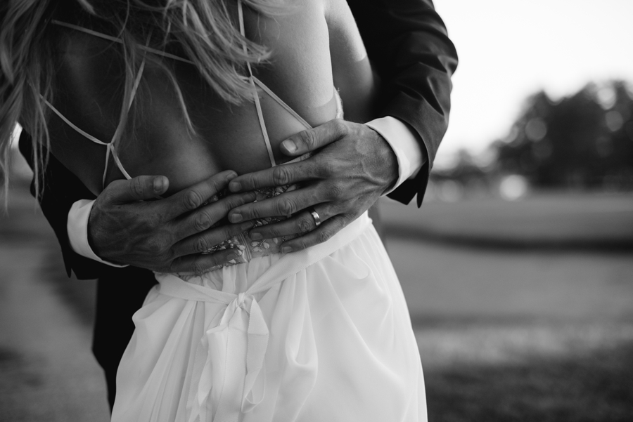 black and white photo of grooms hands around brides back
