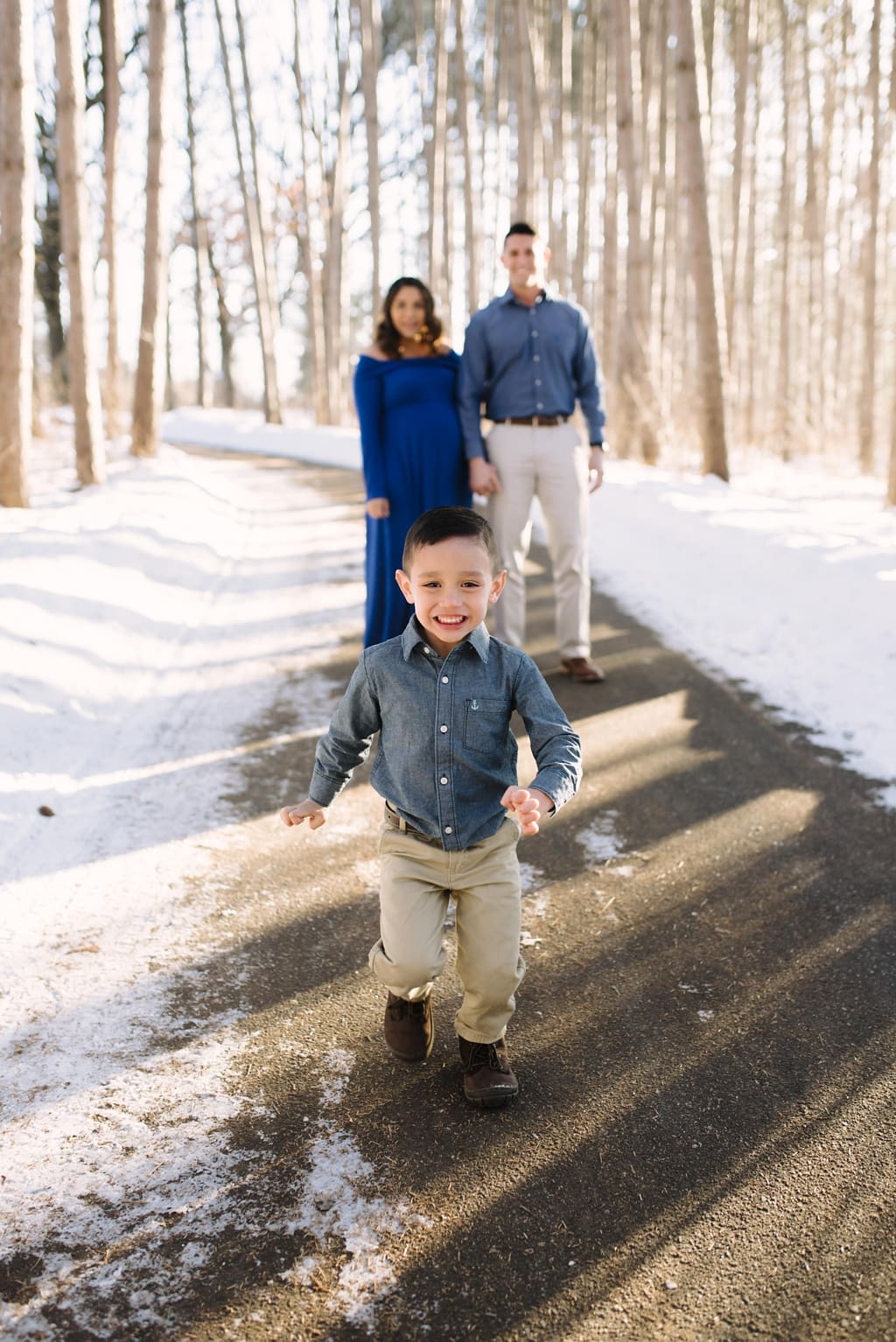 boy runs to camera with parents in background