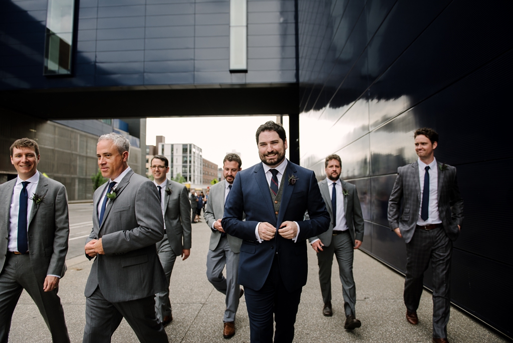 groom and groomsmen walk outside mill city museum