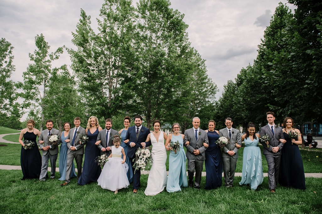 wedding party walks toward camera in outside green area