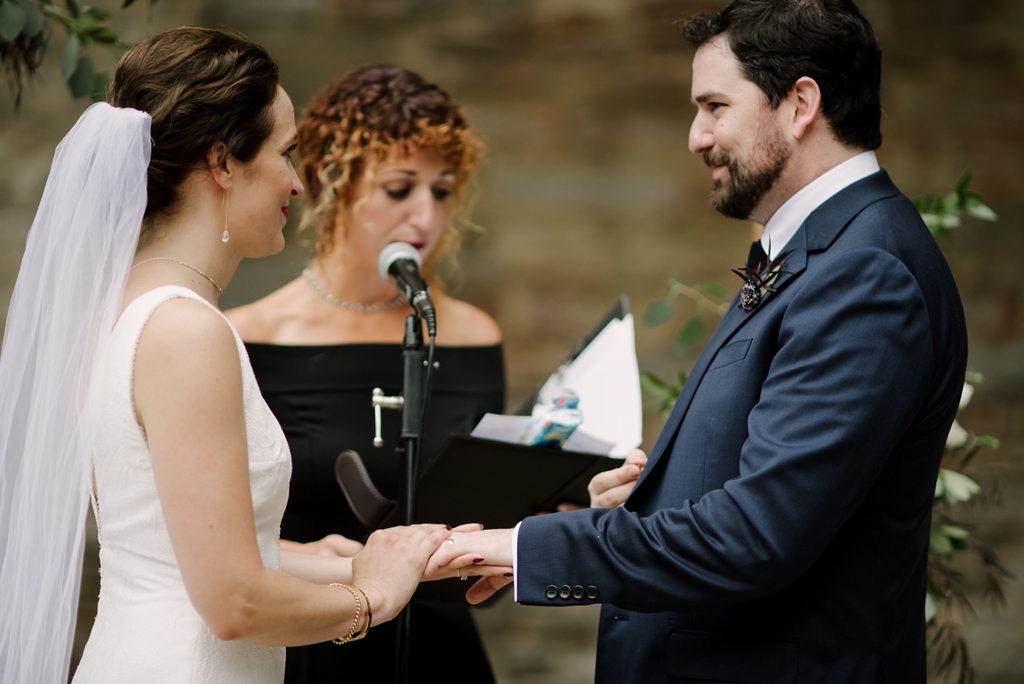 bride and groom holding hands during ring exchange