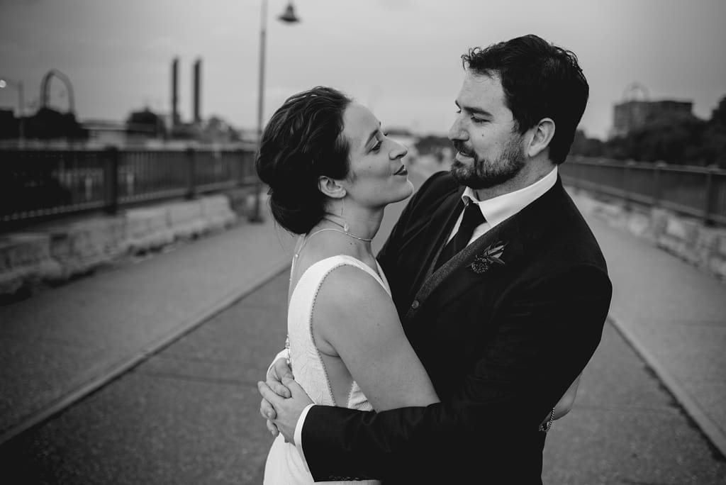 bride and groom embrace on bridge in minneapolis