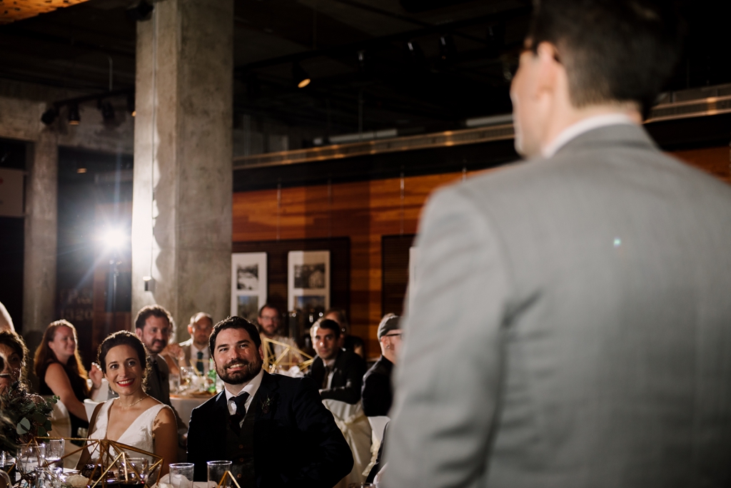 bride and groom listening to speeches at reception