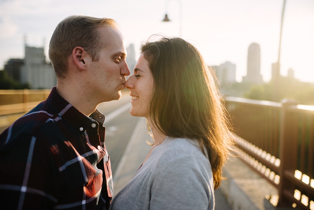 husband kissing wife's nose at sunset on minneapolis bridge