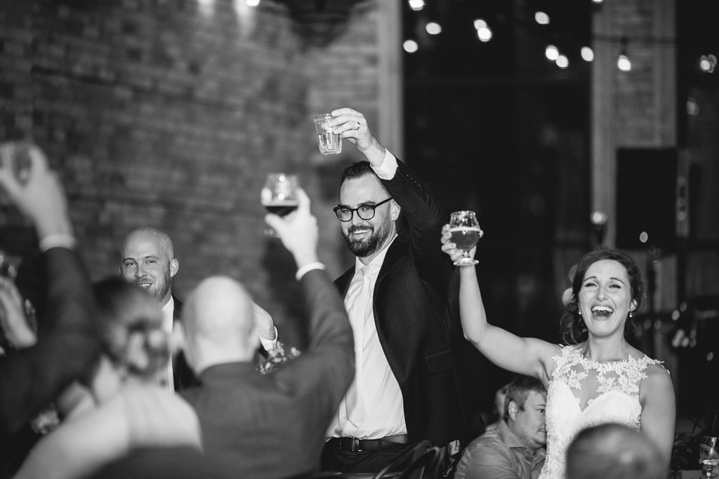 bride and groom lifting glasses to toast at reception