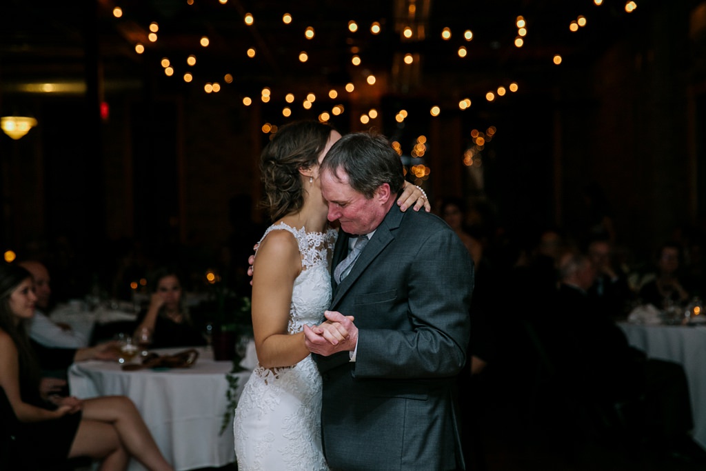 bride dances with father with twinkle lights behind