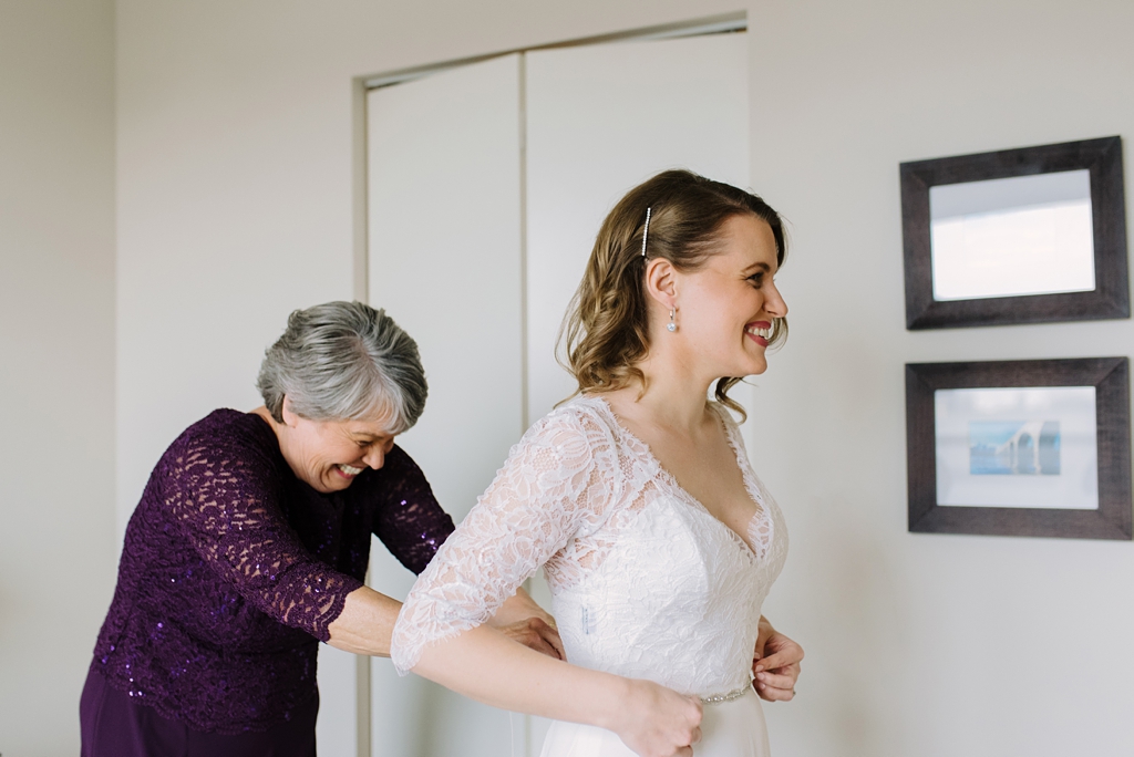 mother zipping bride into dress