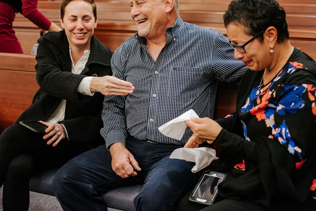 teary wedding guests exchange tissues