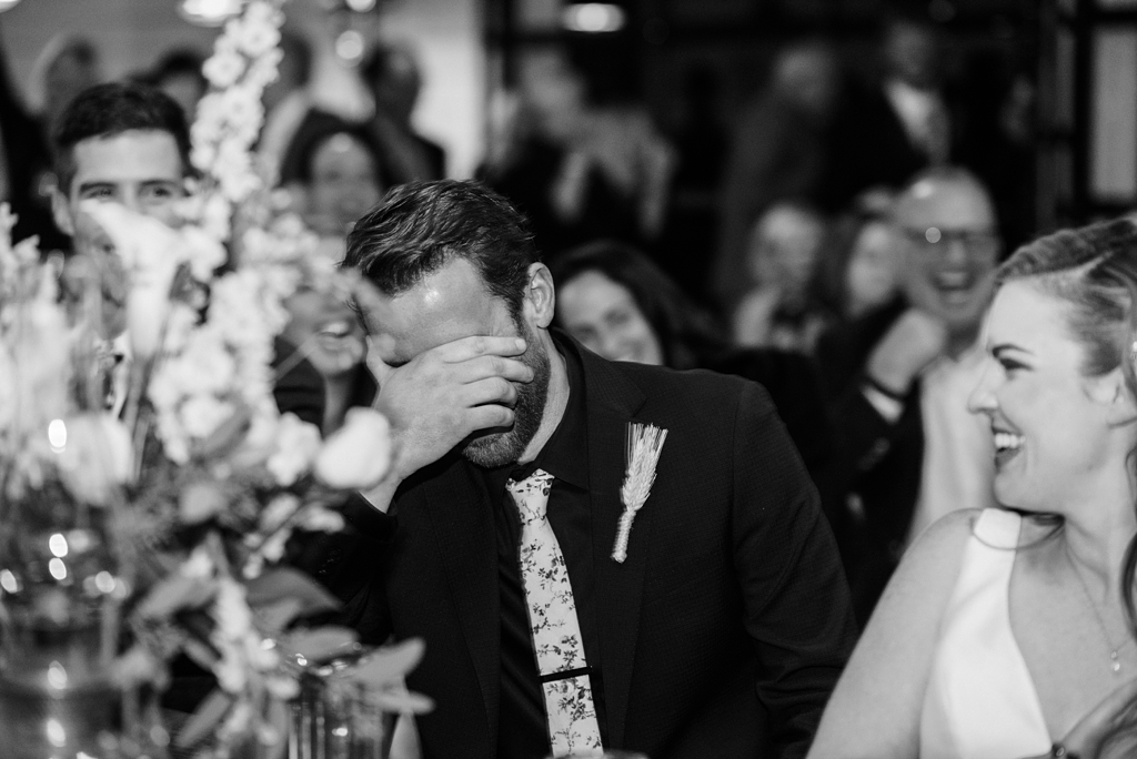 groom covers eyes embarrassed by reception speech