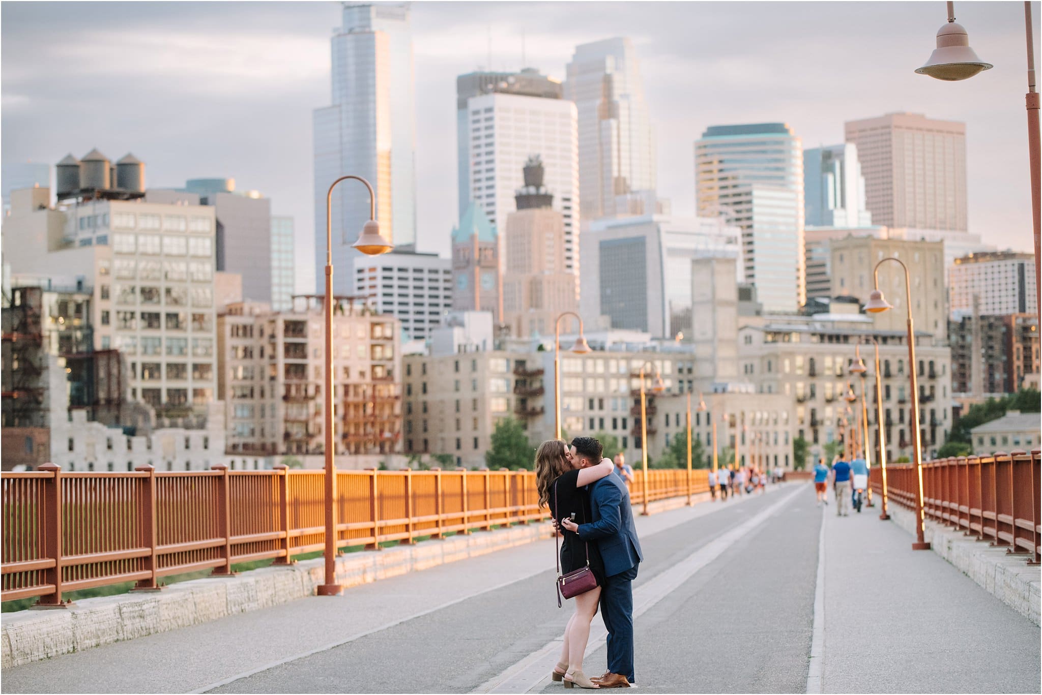 couple embrace on stone arch bridge minneapolis