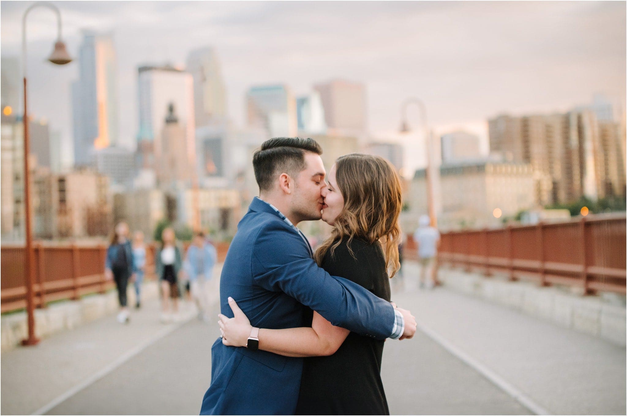 newly engaged couple kisses in front of   skyline