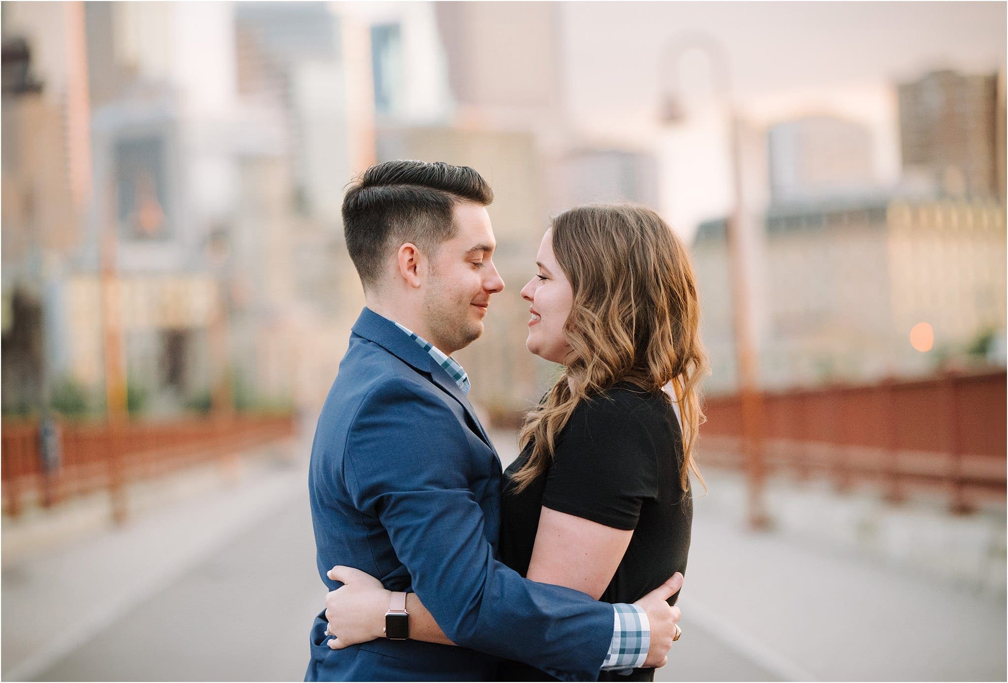 newly engaged couple embraces on stone arch bridge