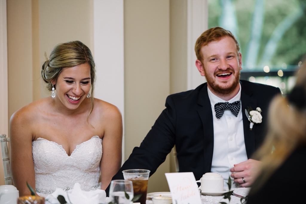 newlyweds enjoy speech at golf club wedding reception