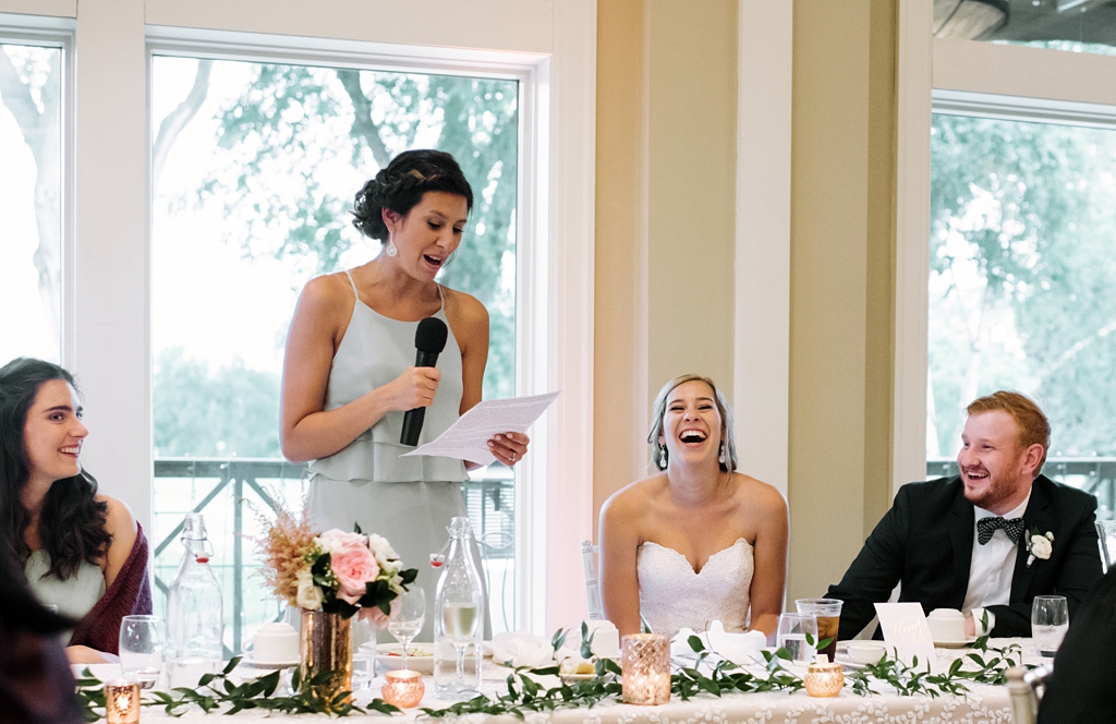 bride laughs at bridesmaid's speech at reception