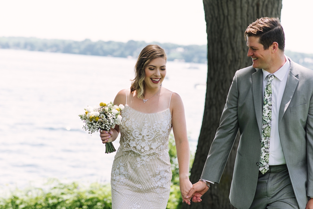 bride and groom walking toward camera away from lake
