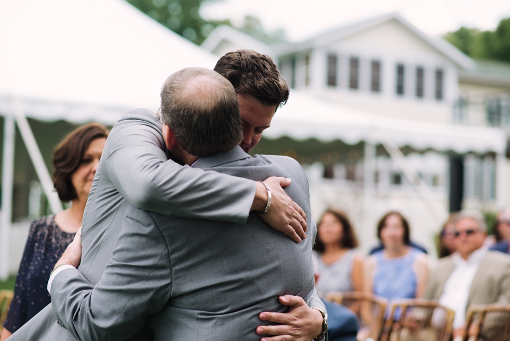groom hugging dad before backyard wedding ceremony