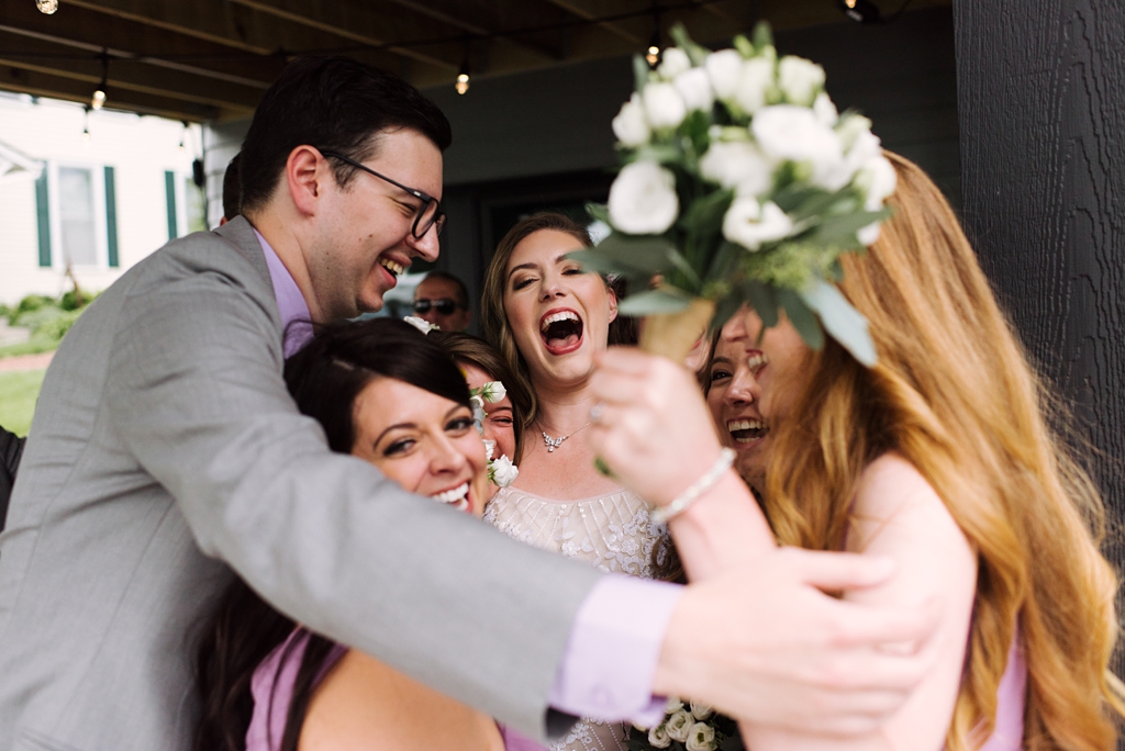 bridal party hugging laughing bride after ceremony