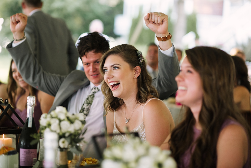 bride laughing while groom fist pumps at reception