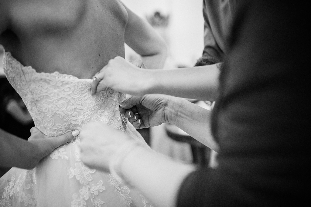 hands fastening bride into her dress