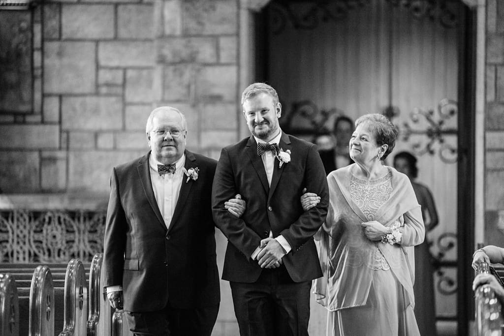 groom escorting parents down aisle