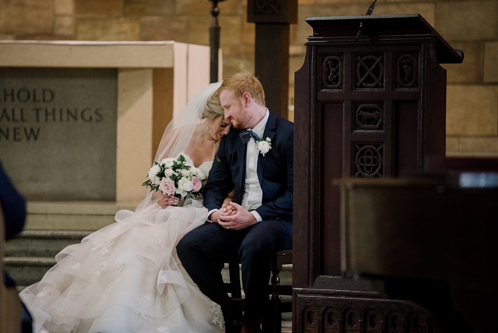 bride and groom sitting together during catholic ceremony