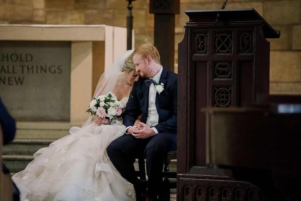 bride and groom sitting together during catholic ceremony