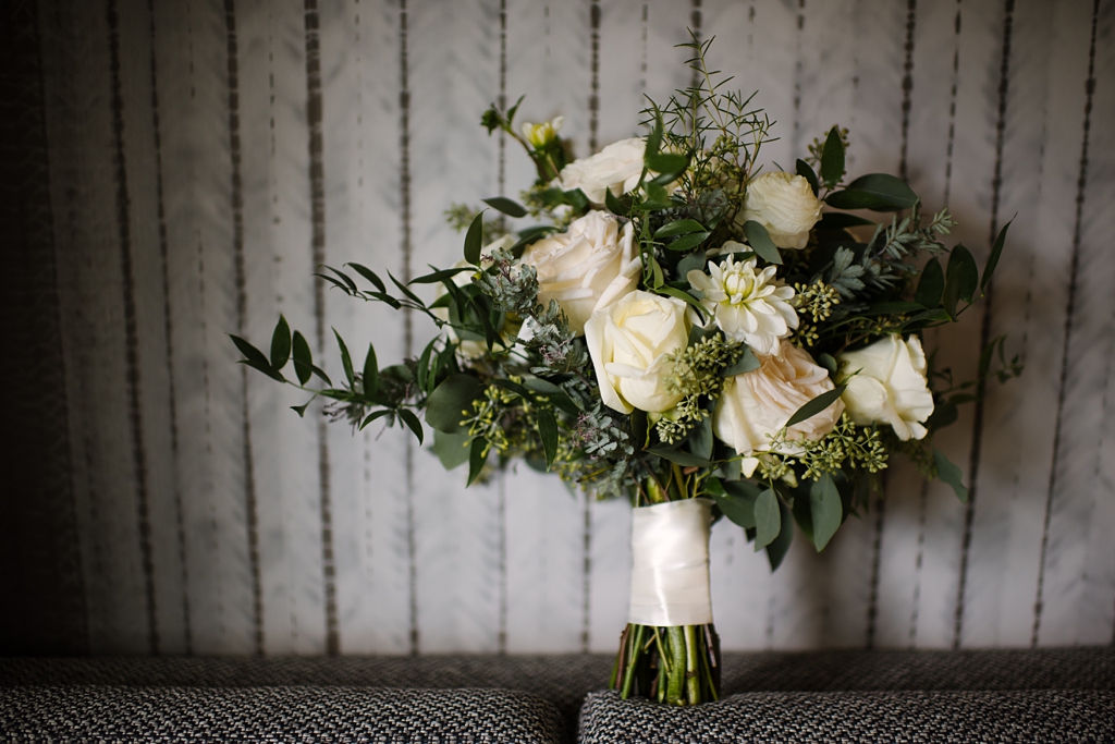 wedding bouquet of roses and greens against simple backdrop