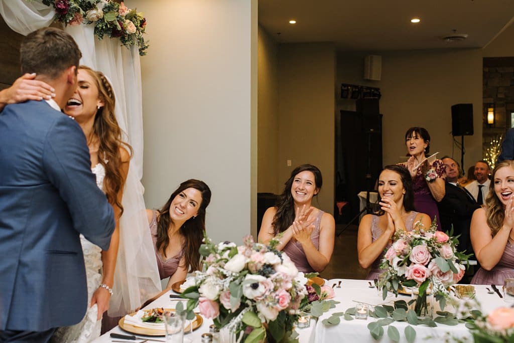 bride and groom kiss during toasts at wedding reception