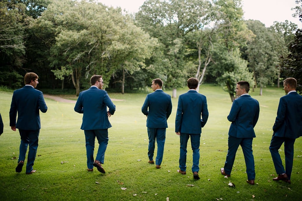 groom and groomsmen walk away across open green