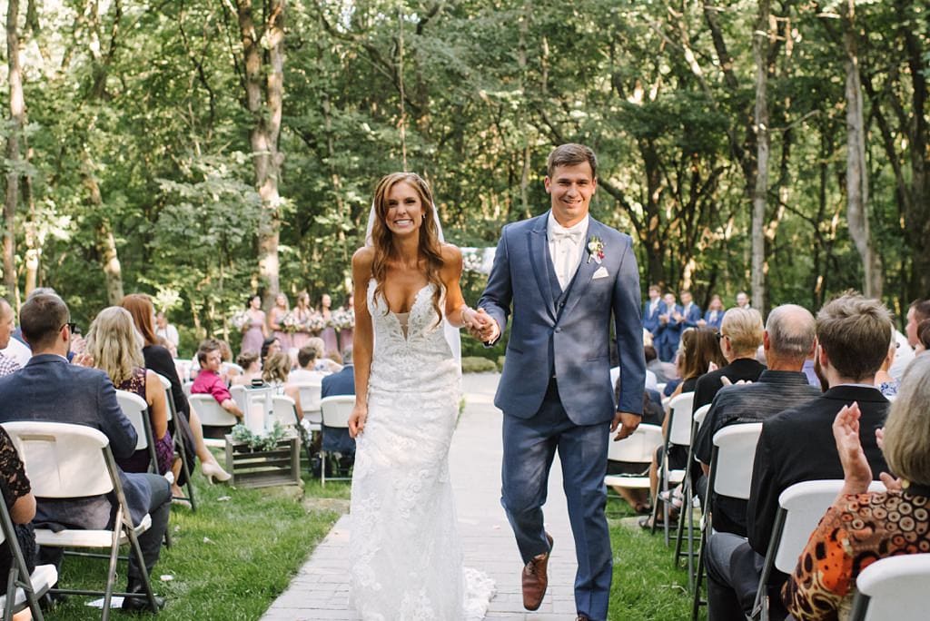 excited newlyweds walk down aisle