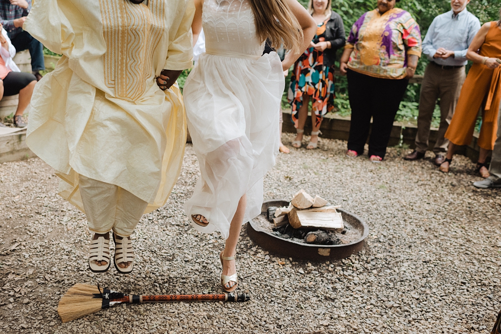 bride and groom jump the broom at outdoor wedding