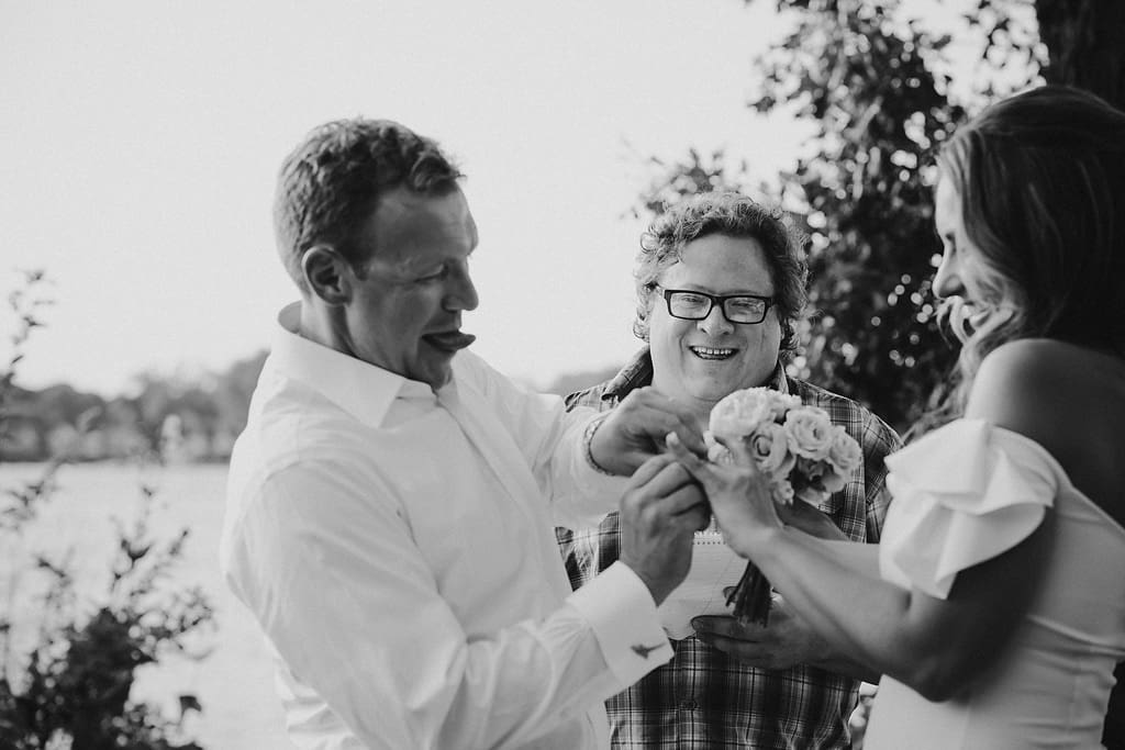 bride laughs at groom struggling with wedding ring
