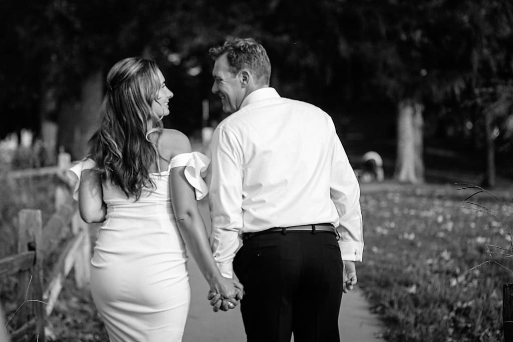 bride and groom hold hands and walk away down path