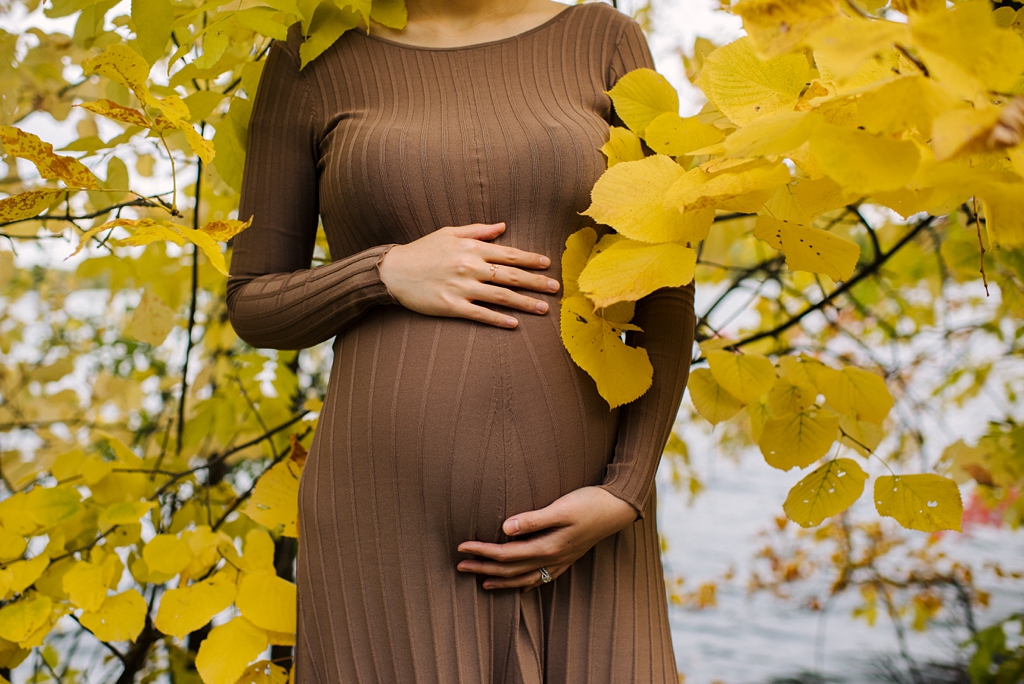 expectant mother poses among yellow fall folliage