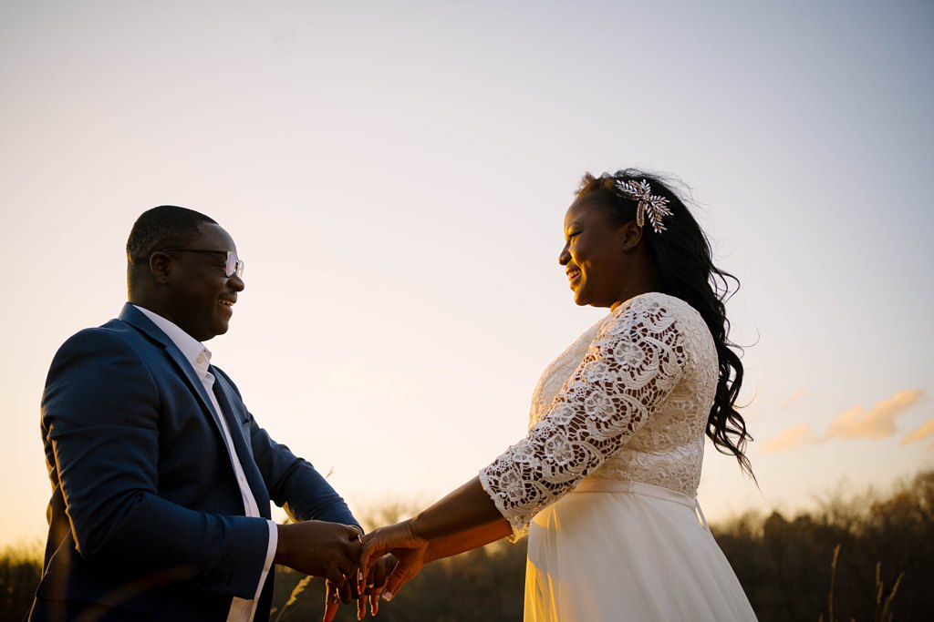newlywed couple at sunset dancing in field
