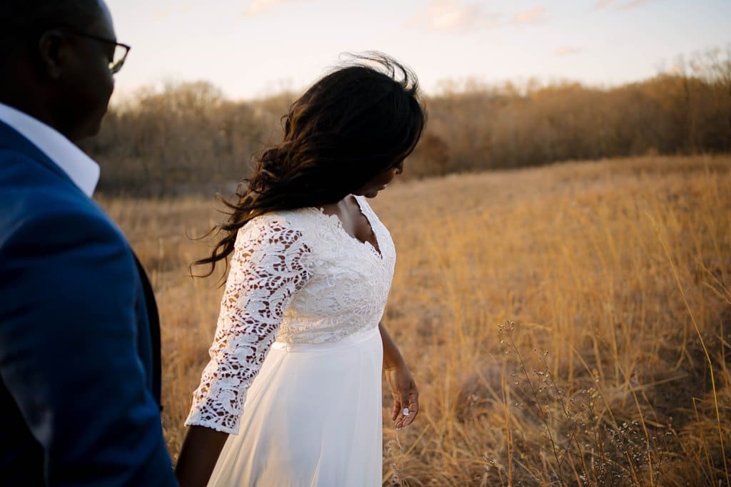 minnesota couple walking through golden field at sunset