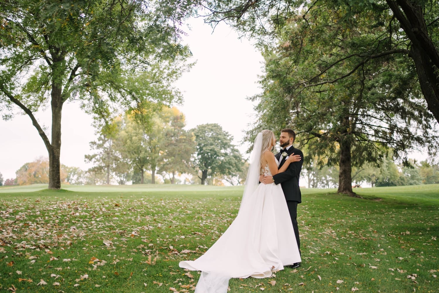 minneapolis newlyweds posing outside with fall leaves