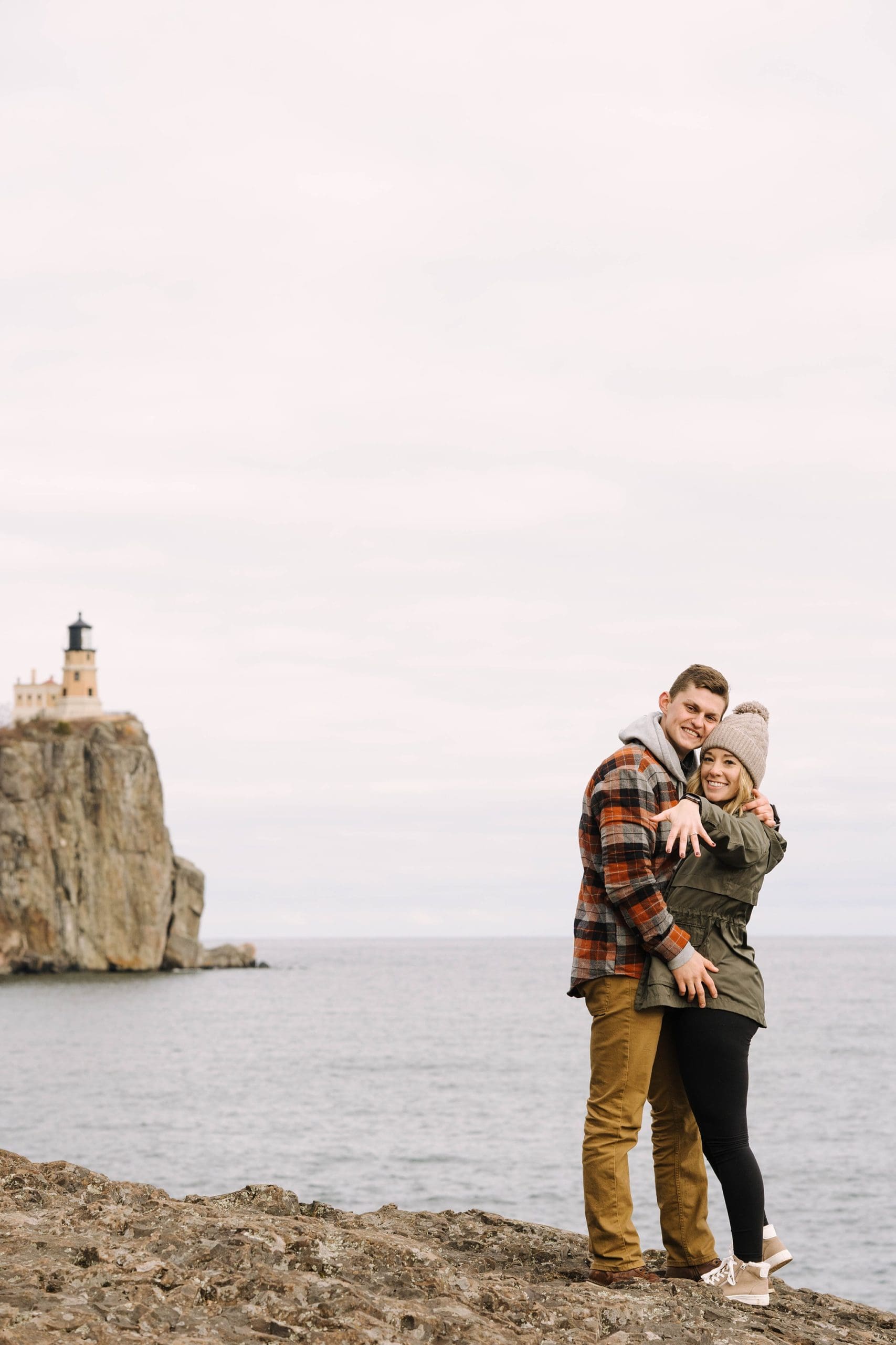 newly engaged couple show off engagement ring lakeside