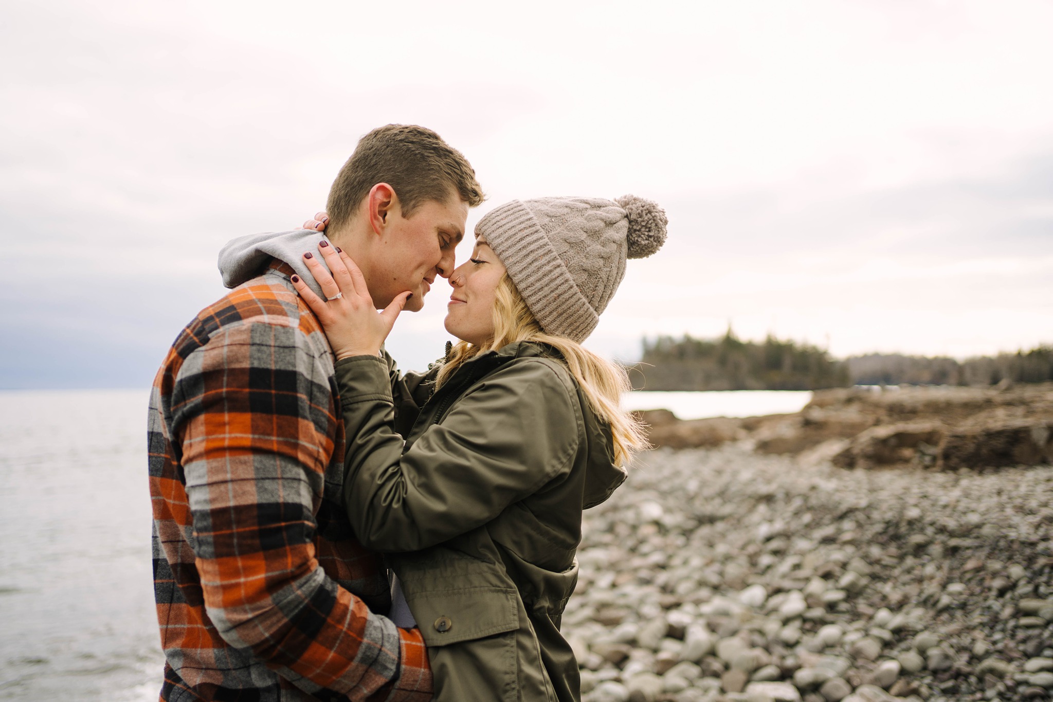 newly engaged couple kissing beside lake superior