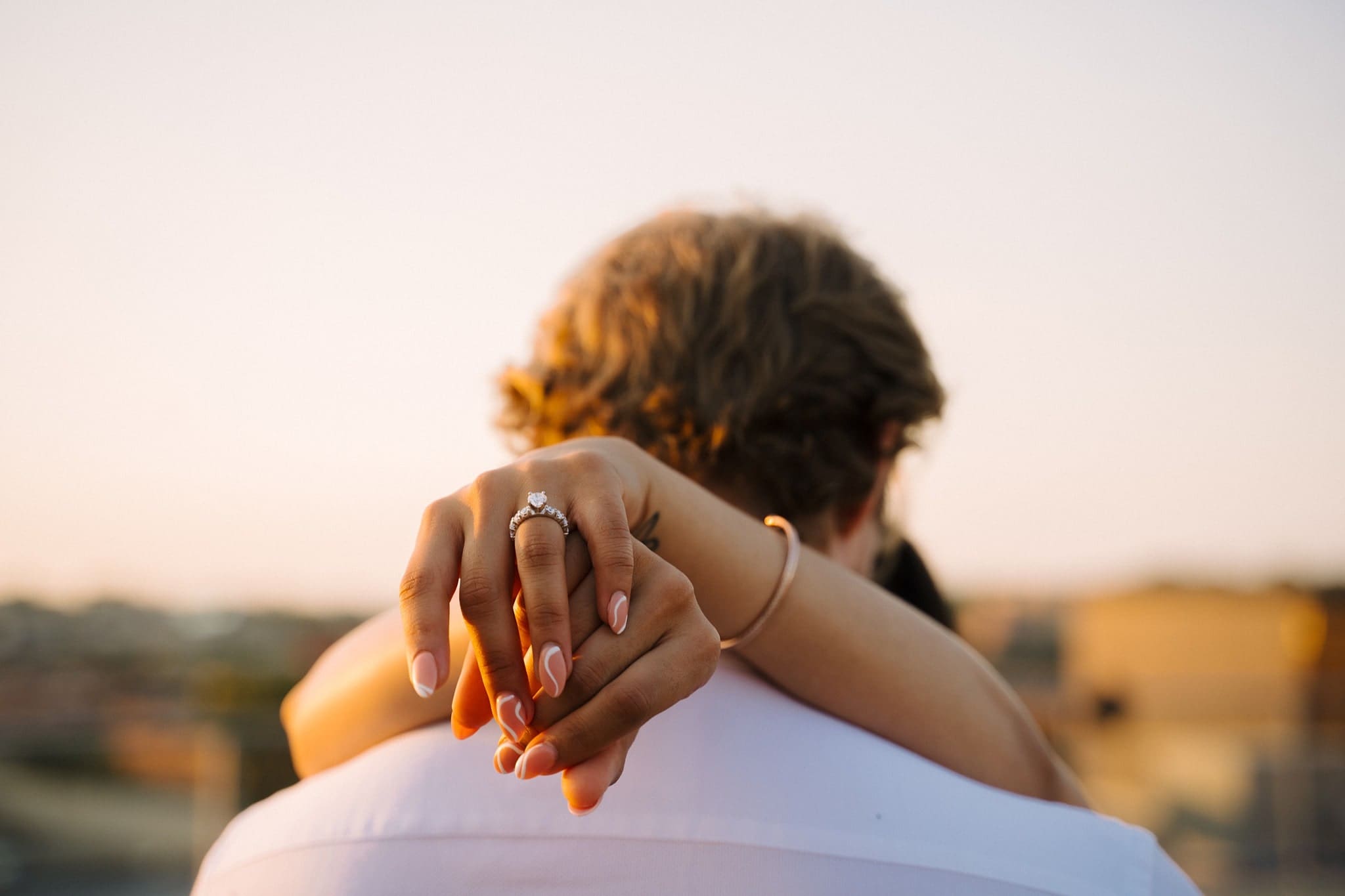 engaged couple embrace showing off engagement ring