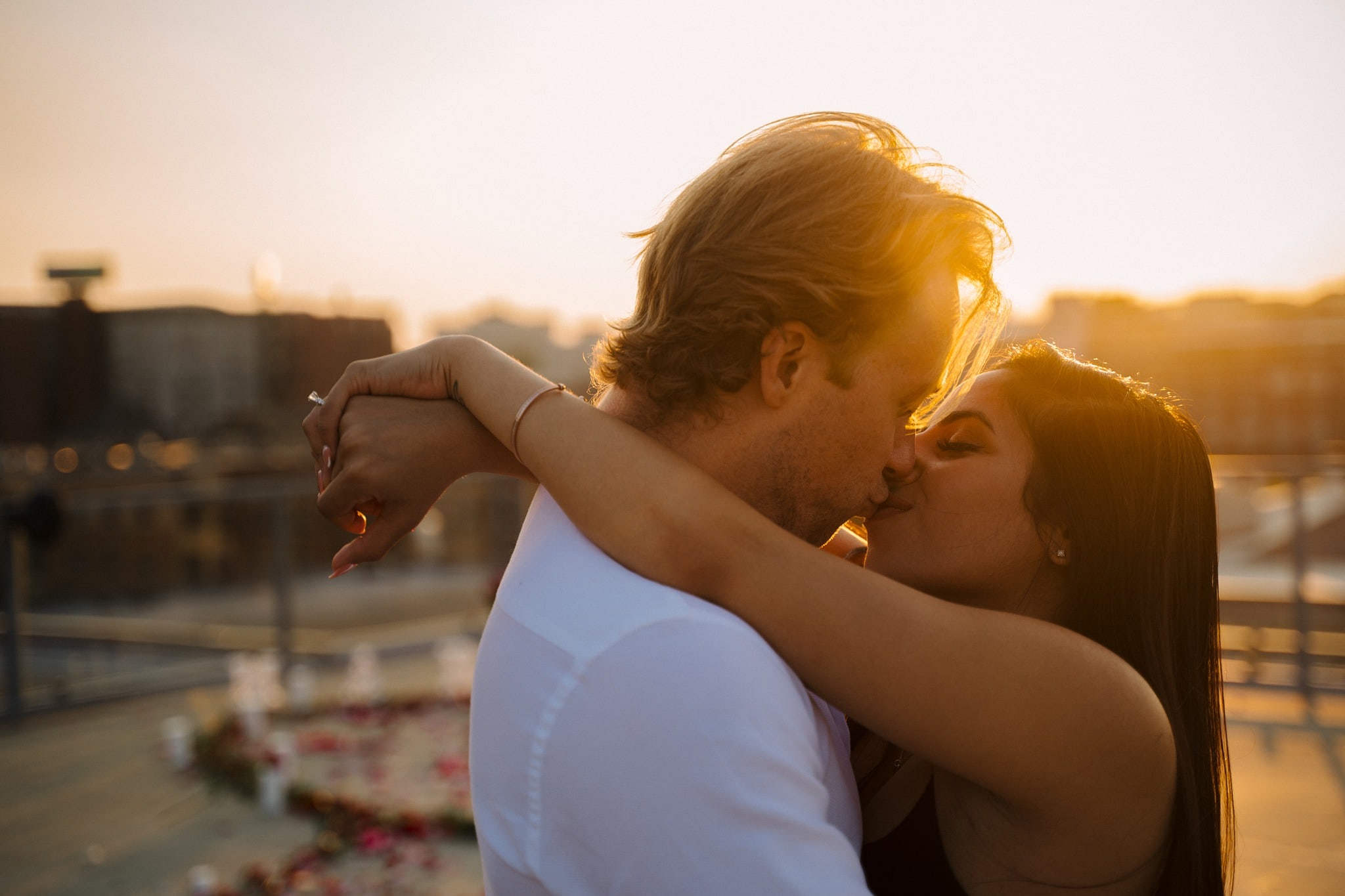 engaged couple kissing in sunset light