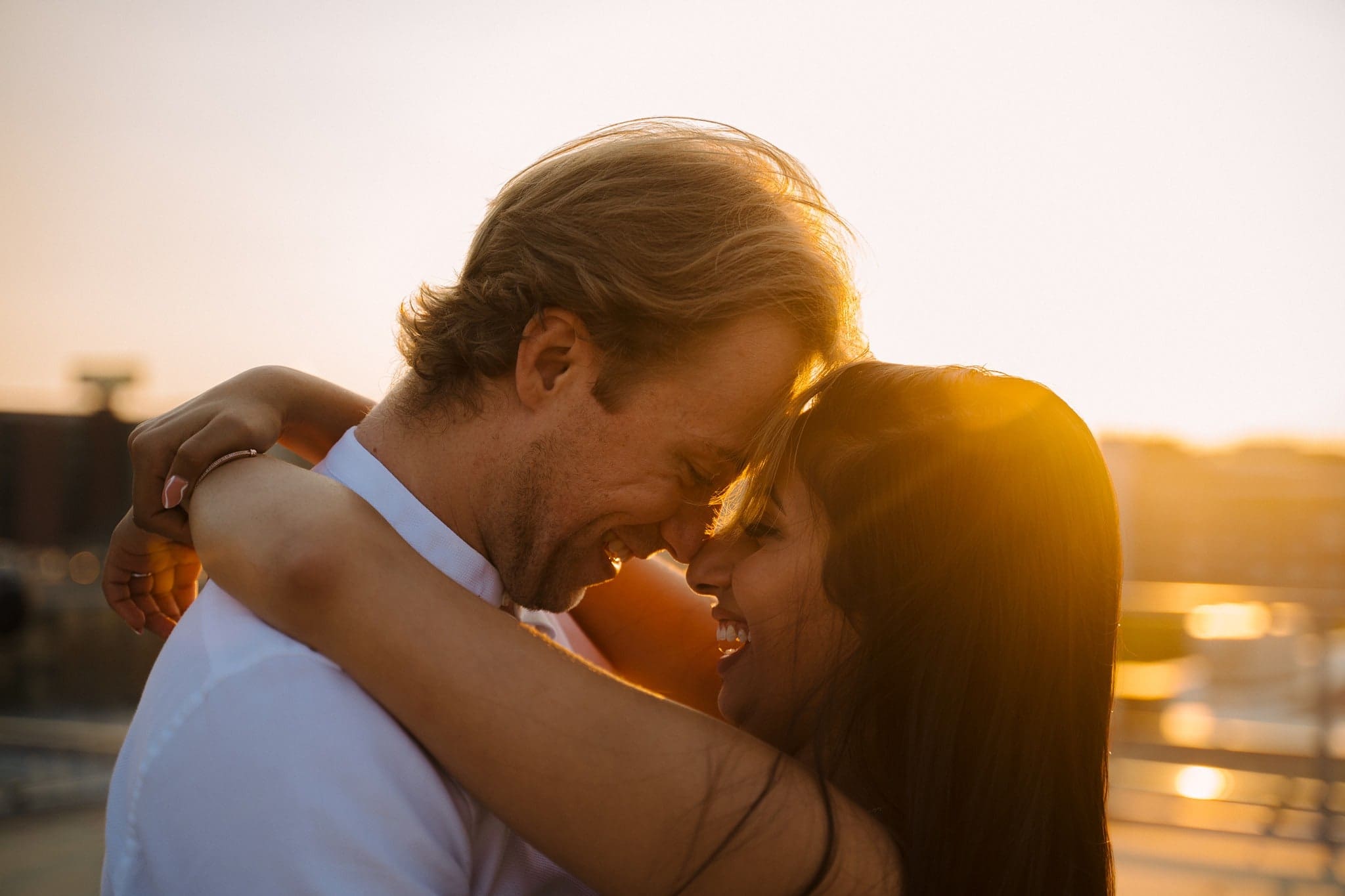 laughing couple embrace at sunset after A'bulae rooftop proposal