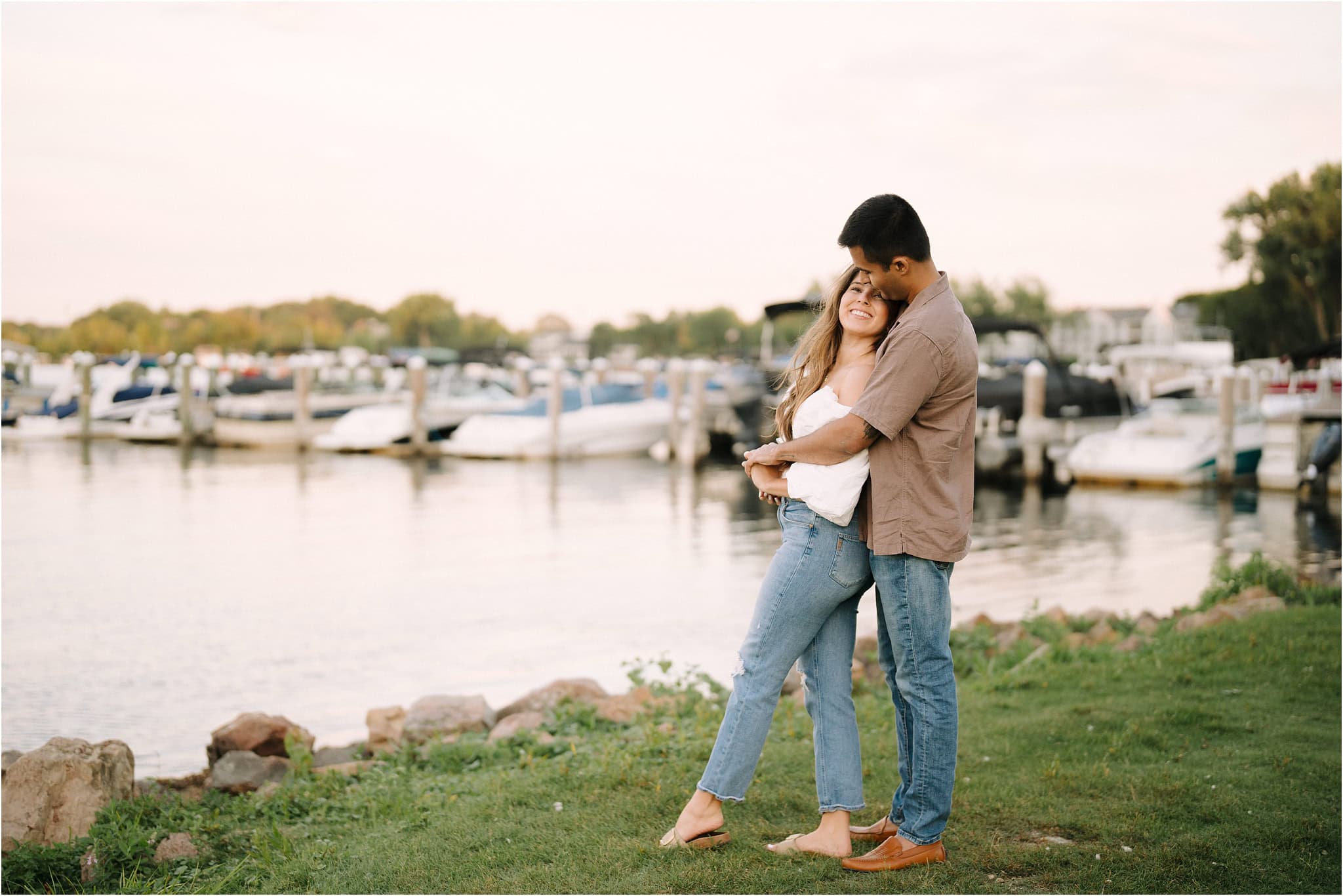 A man gazing lovingly at his smiling fiancée as they stand beside the lake near Port Excelsior.